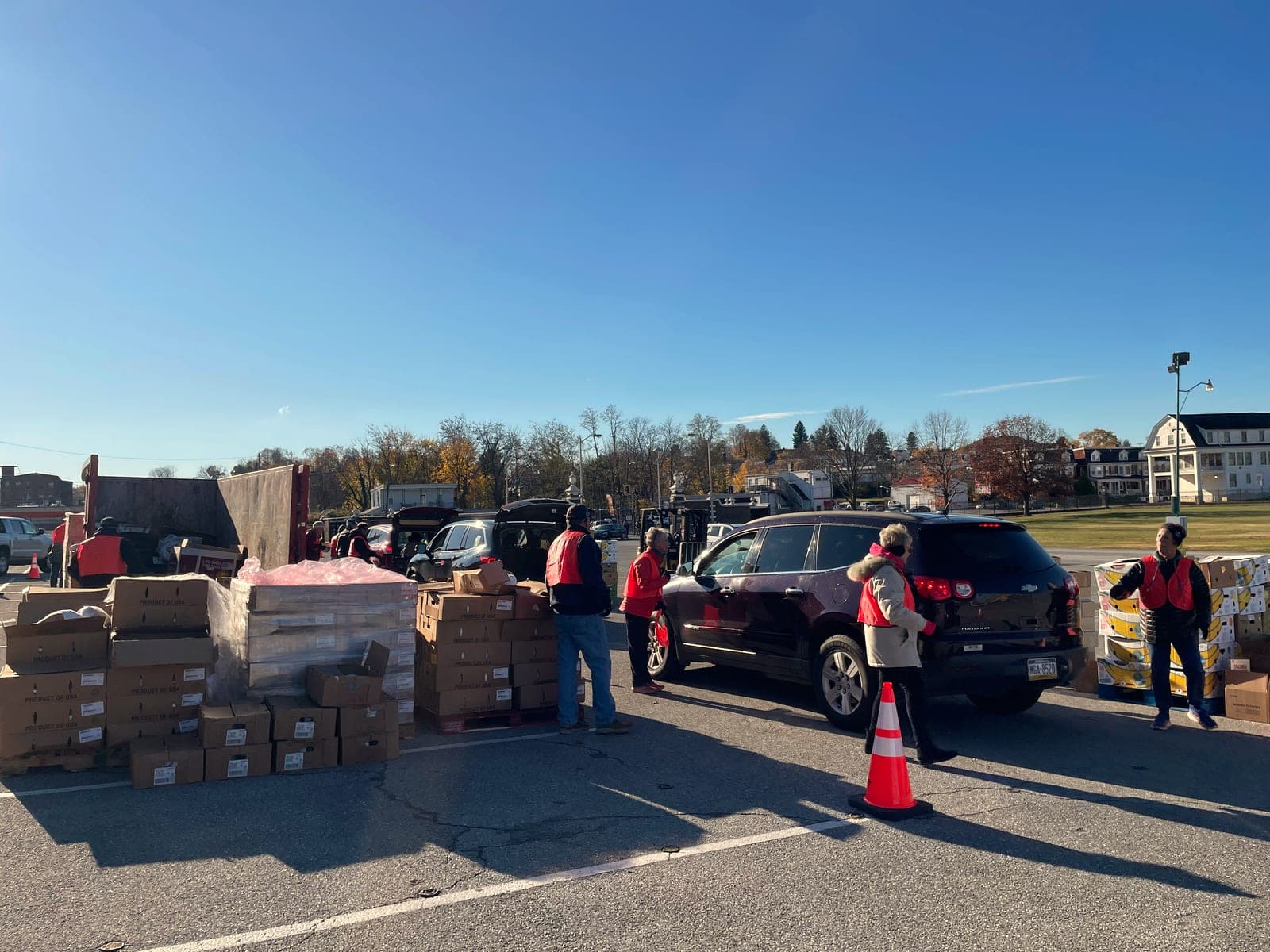 Volunteers in red vests at a drive-through pickup line.